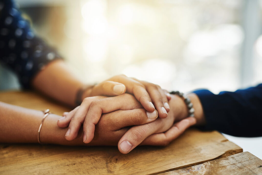 the hands of two people are shown, one grasping the other's hands