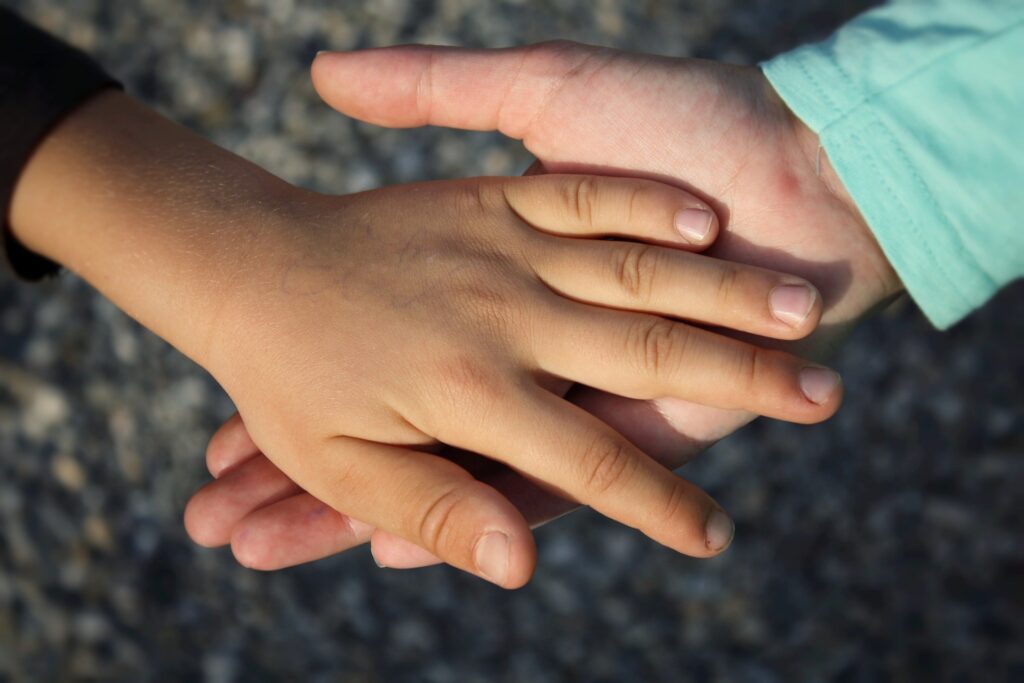 two children's hands holding each other