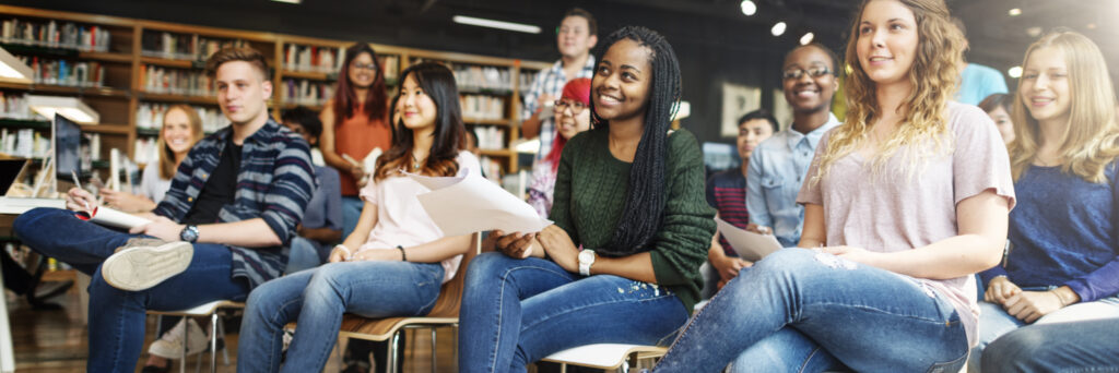 smiling students look attentively to the front of a classroom